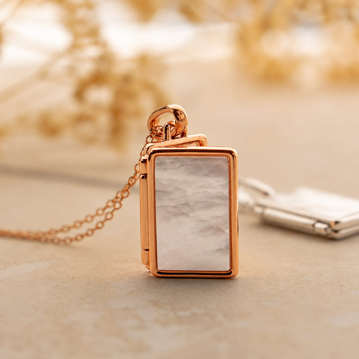 Rose gold rectangular pendant with marble texture on a neutral background
